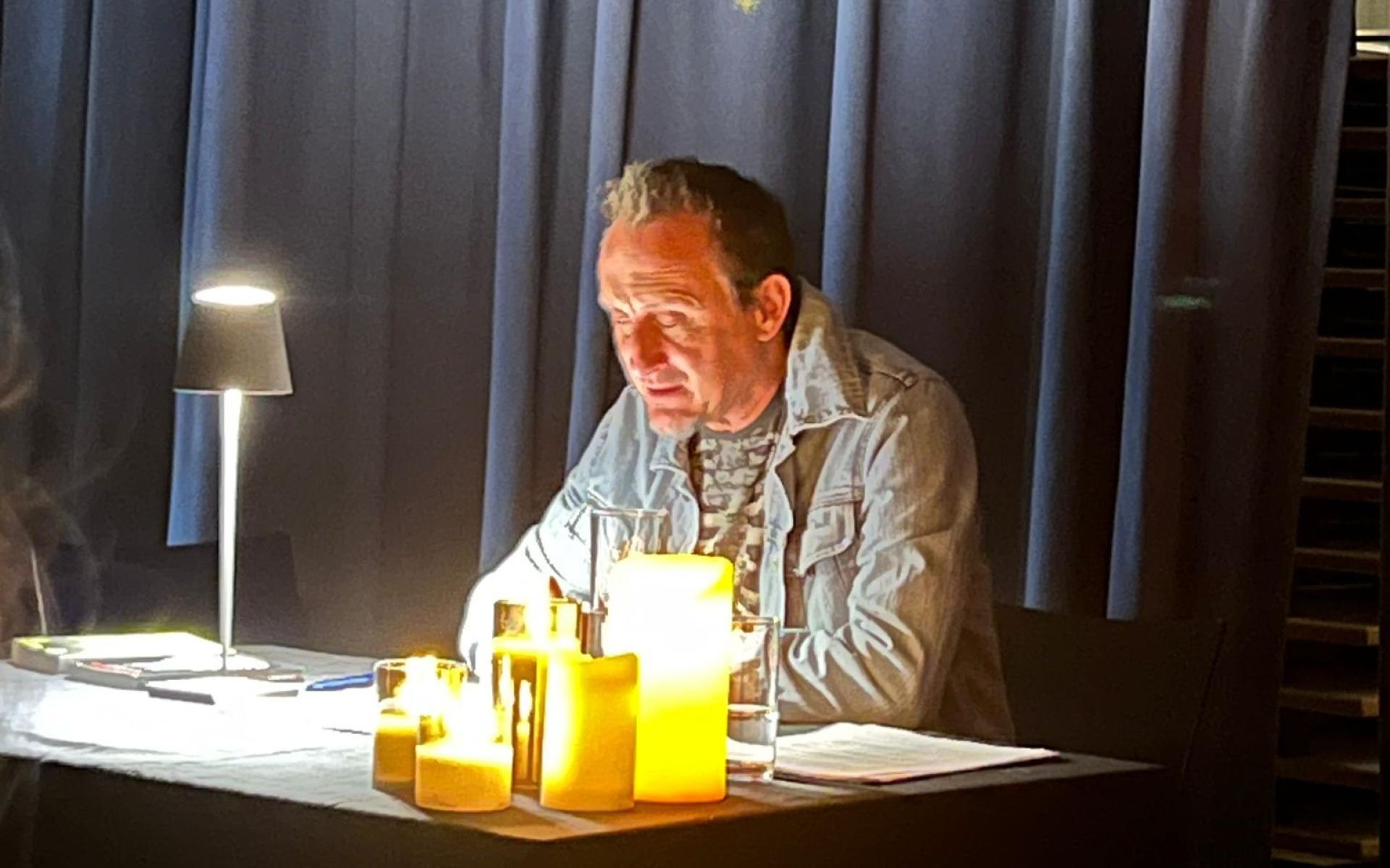 Ein Herr liest im Kerzenlicht